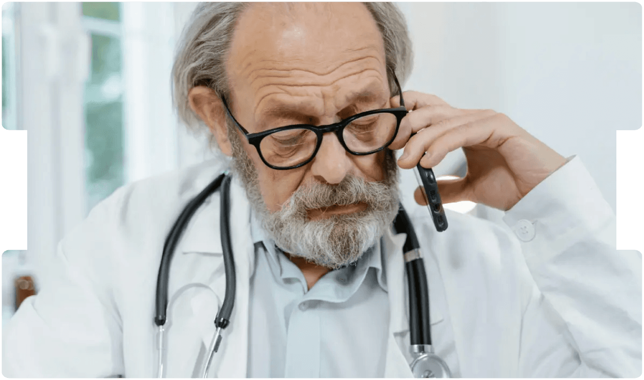 Doctor speaking on the phone while reviewing notes, symbolising clear communication and diligence in clinical negligence case screening.