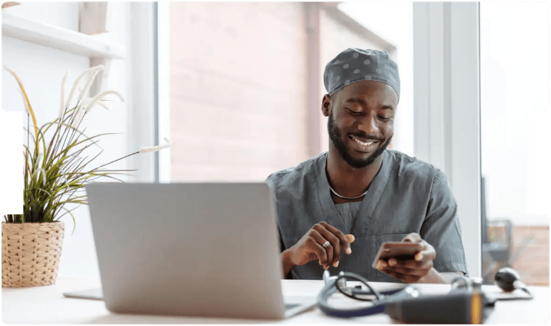 Smiling doctor using a smartphone and laptop, representing the growing role and medico-legal considerations of virtual medical consultations.