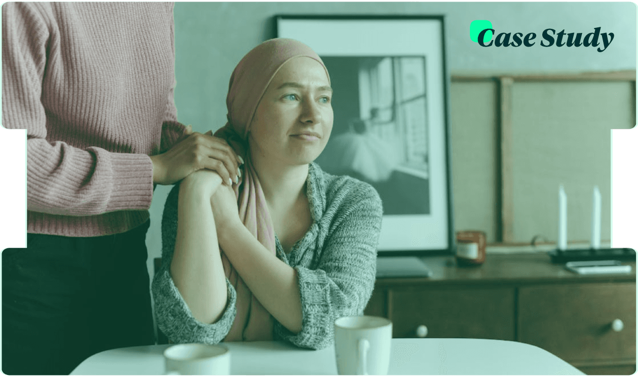 Young woman in a pink headscarf sits at a table as a loved one holds her arm, showing compassionate cancer support and emotional care at home.