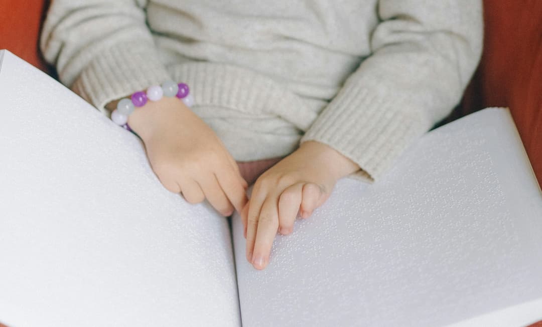 Child reading a braille book, symbolising the impact of cerebral visual impairment and its medico-legal considerations in paediatric care.