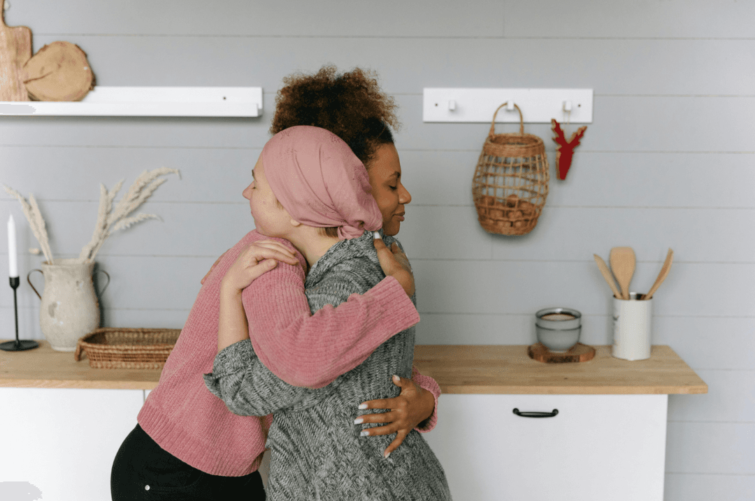 Woman wearing a headscarf hugging a friend in support, symbolising the emotional impact and challenges of late colorectal cancer diagnosis.