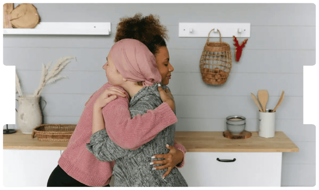 Woman wearing a headscarf hugging a friend in support, symbolising the emotional impact and challenges of late colorectal cancer diagnosis.