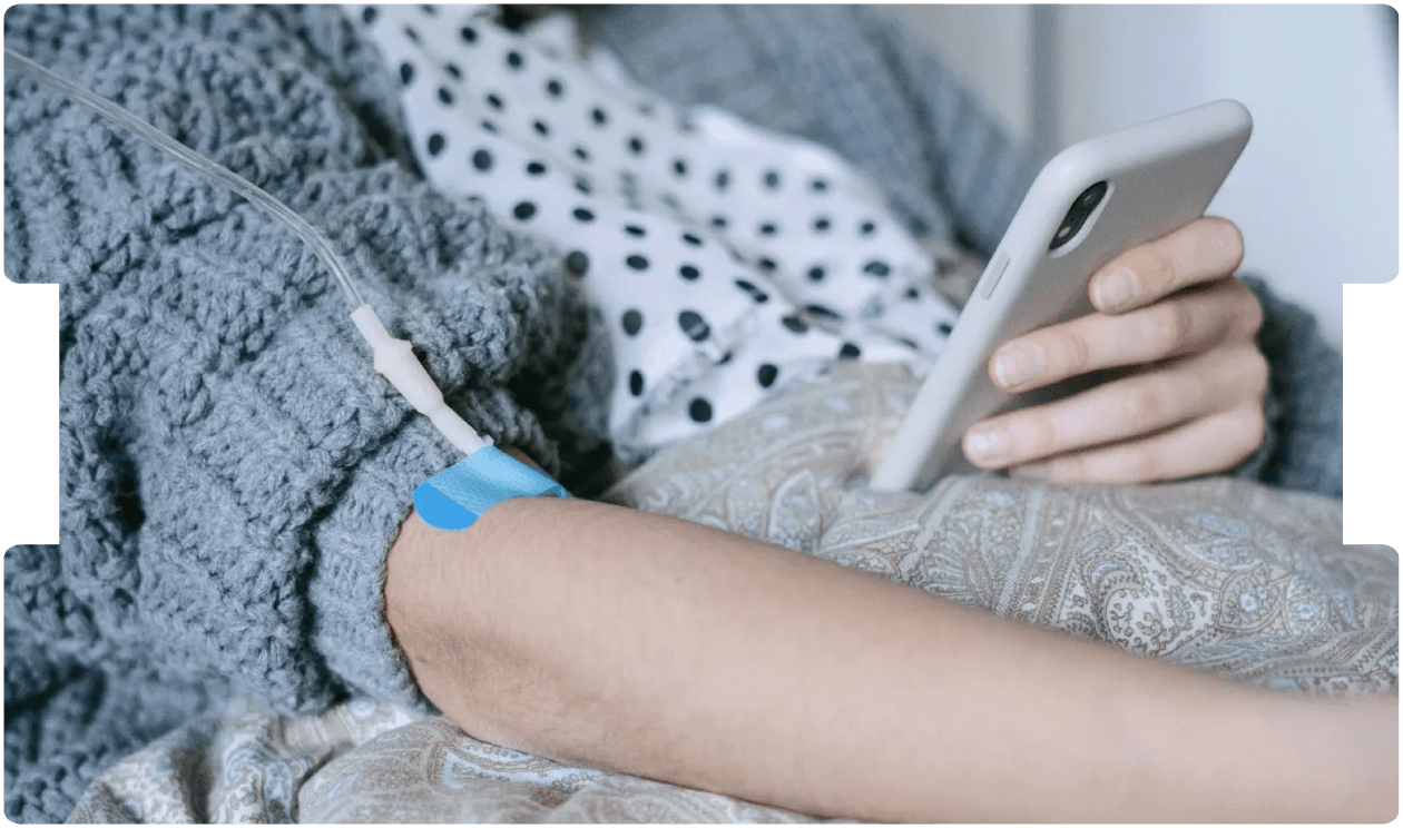 Patient receiving IV treatment while using a phone, illustrating the human impact and legal implications of delayed lung cancer diagnosis.