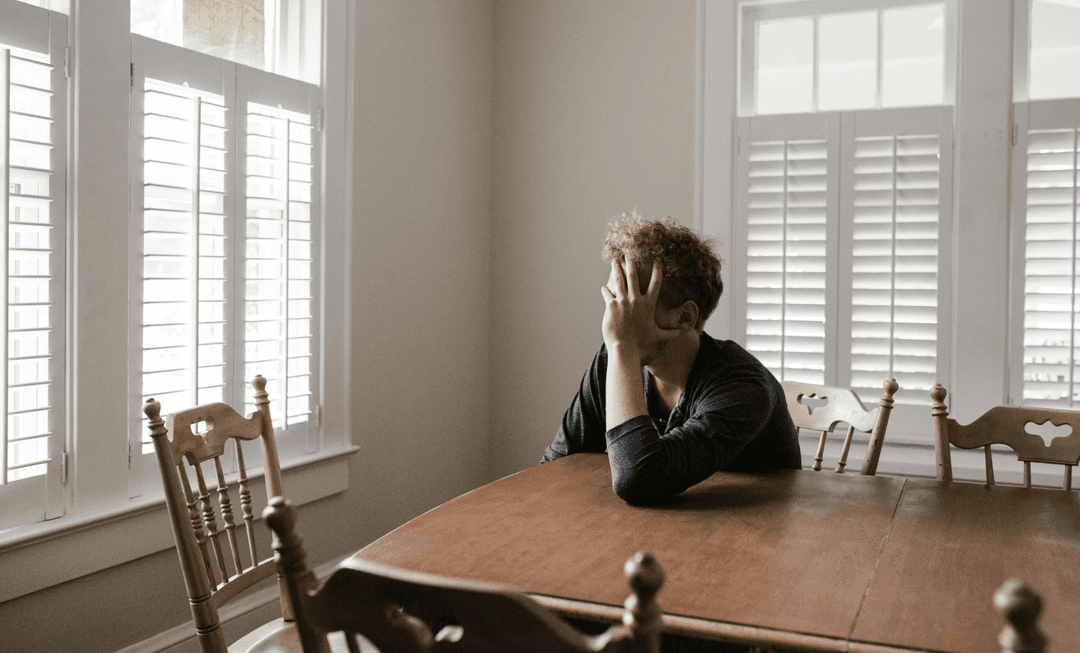 Man sitting alone at a table appearing distressed, symbolising the emotional and behavioural complexities of personality disorders.