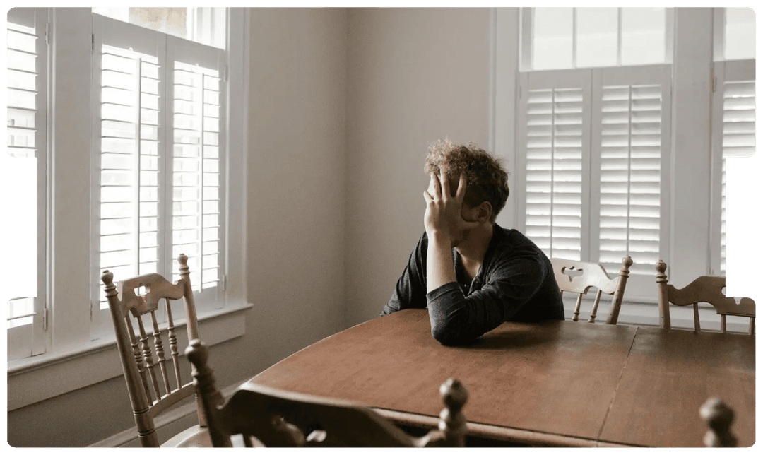 Man sitting alone at a table appearing distressed, symbolising the emotional and behavioural complexities of personality disorders.