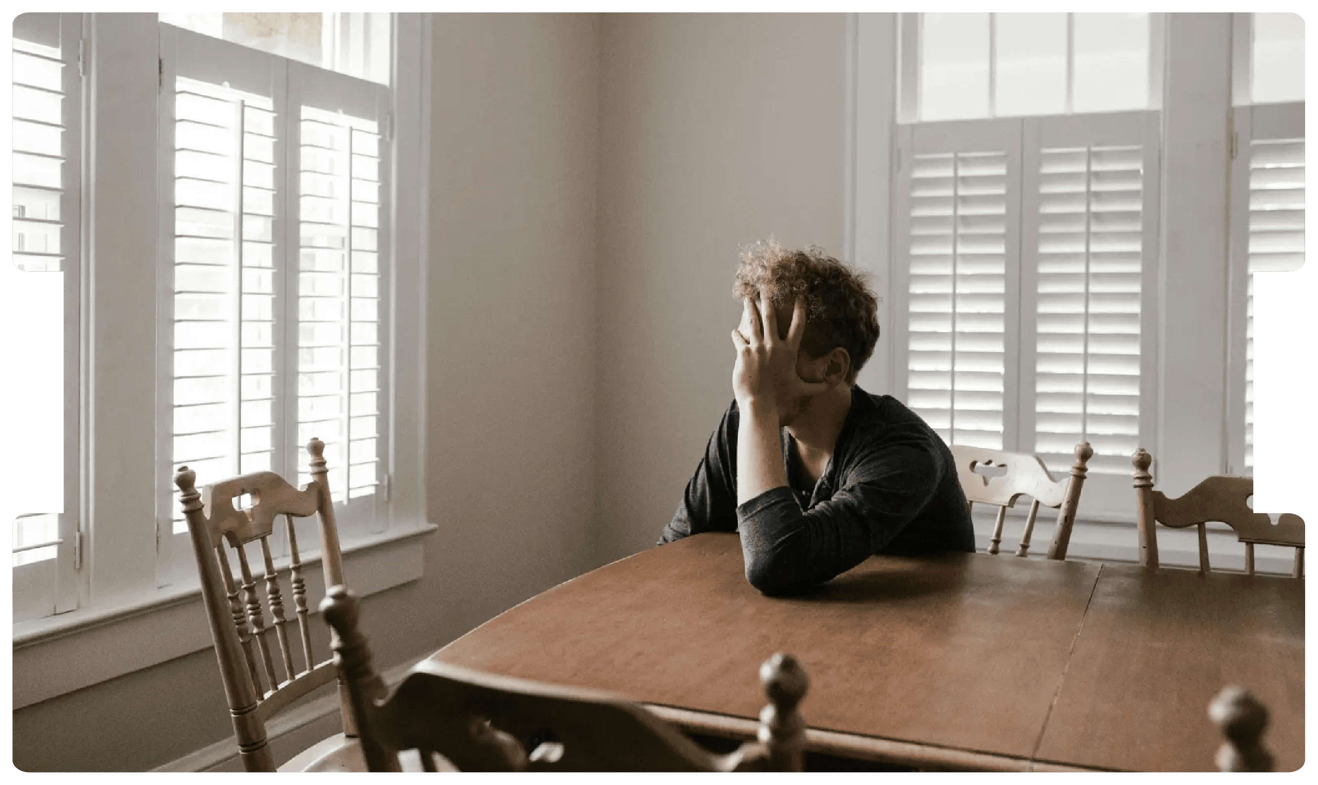 Man sitting alone at a table appearing distressed, symbolising the emotional and behavioural complexities of personality disorders.