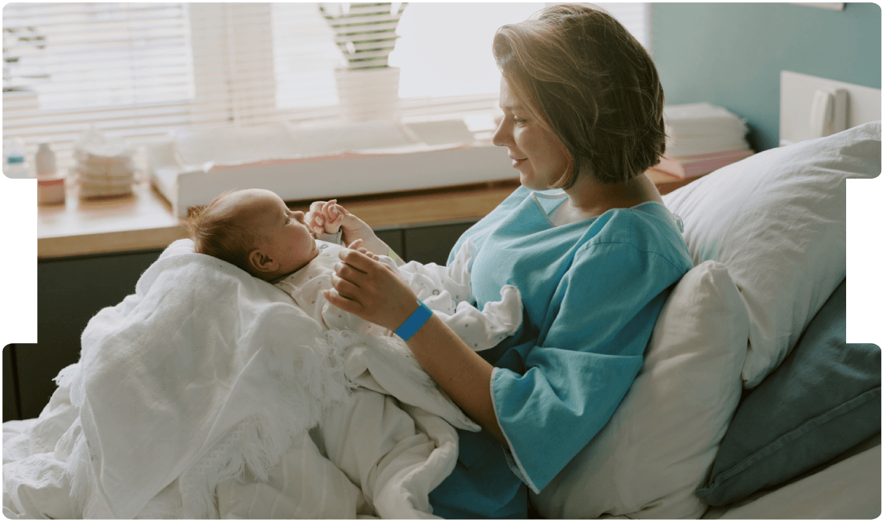 New mother cradles her newborn in a bright hospital room, reflecting gentle maternity care and supportive postnatal recovery.