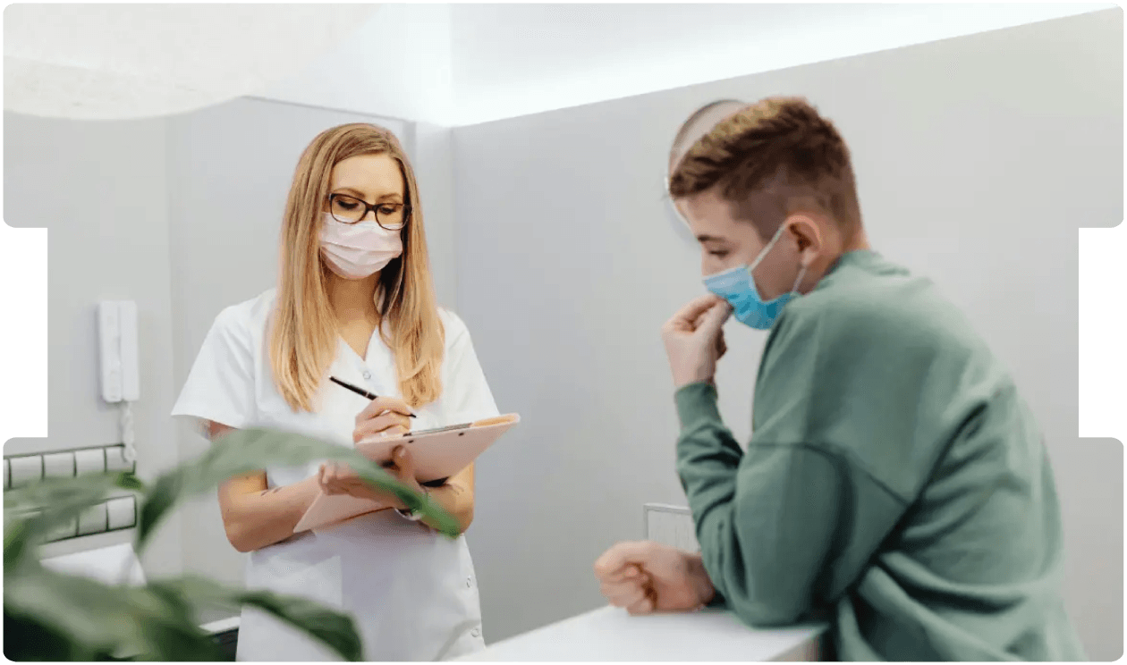 Healthcare professional consulting a patient while wearing masks, reflecting adaptations in medico-legal reporting during the COVID-19 pandemic.