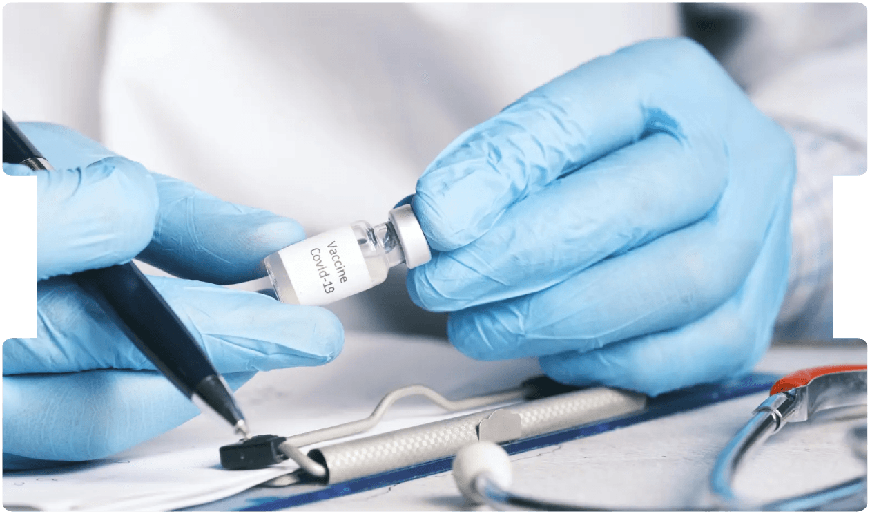 Doctor holding a COVID-19 vaccine vial while making notes, representing key medico-legal considerations surrounding vaccination and consent.