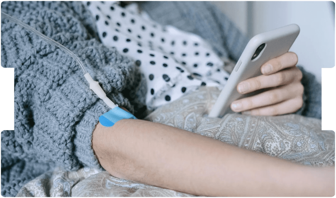 Patient receiving IV treatment while using a phone, illustrating the human impact and legal implications of delayed lung cancer diagnosis.