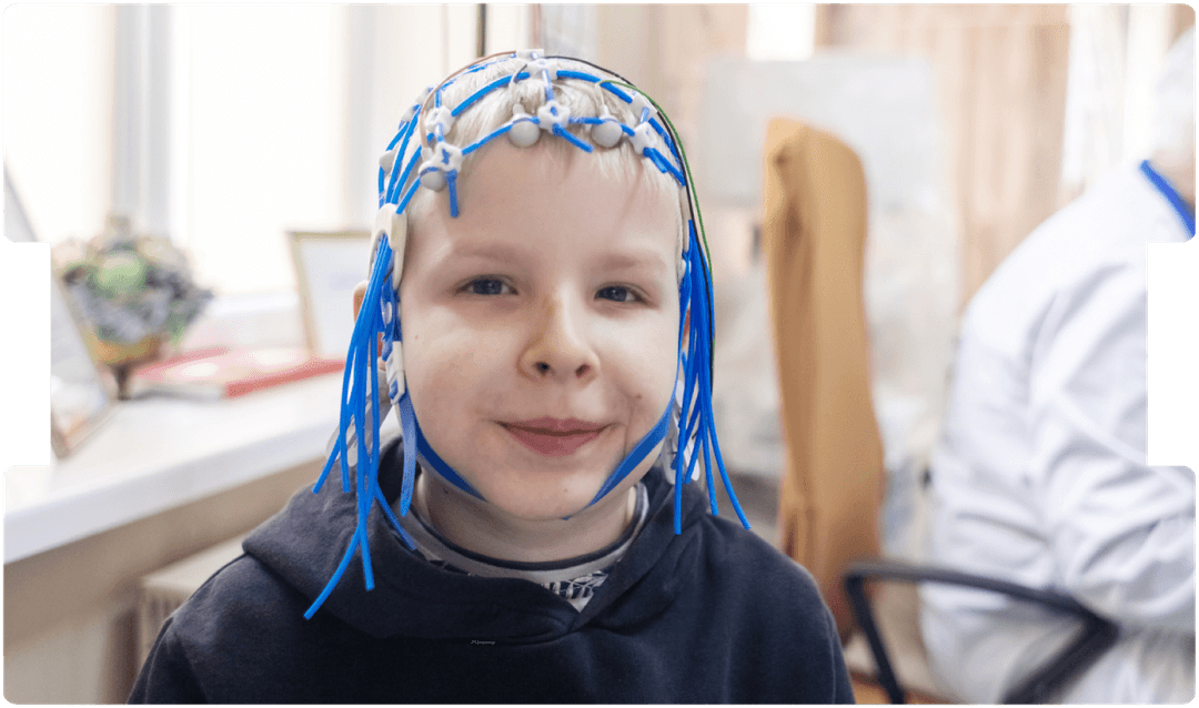 Child sits calmly during a paediatric EEG exam, supporting gentle neurological assessment with specialist brain-activity monitoring.