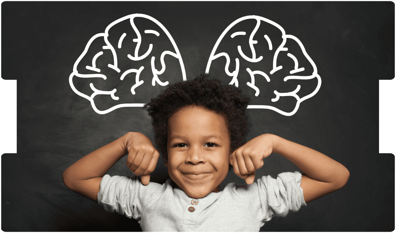 Smiling child flexing arms in front of a chalkboard with brain drawings, symbolizing recovery and strength after paediatric traumatic brain injury.