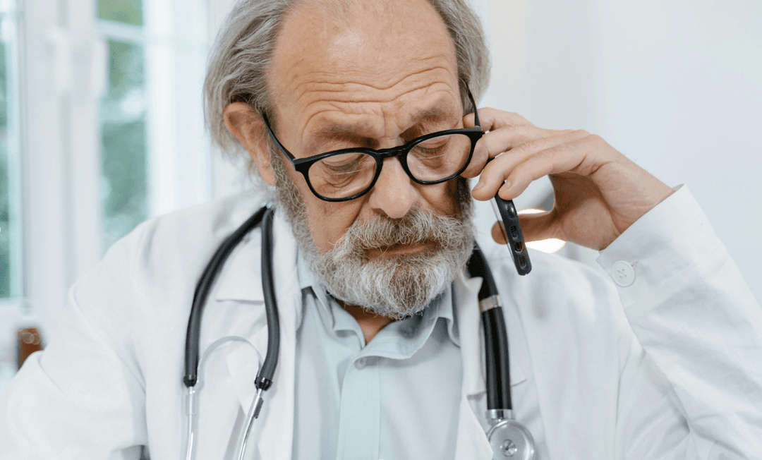 Doctor speaking on the phone while reviewing notes, symbolising clear communication and diligence in clinical negligence case screening.